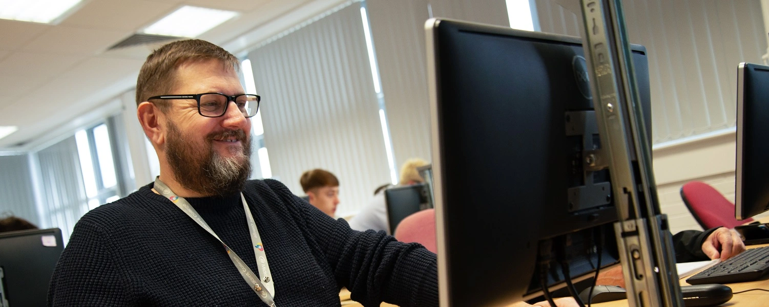 Smiling adult working at an iMac computer